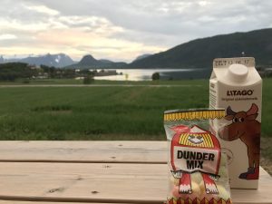 Dunder Mix candies and chocolate milk on a picnic table with the fjord scenery in the background